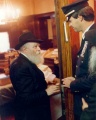 שוטר עובר לפני הרבי בחלוקת לעקאח בערב יום הכיפורים בפתח חדרו של הרבי